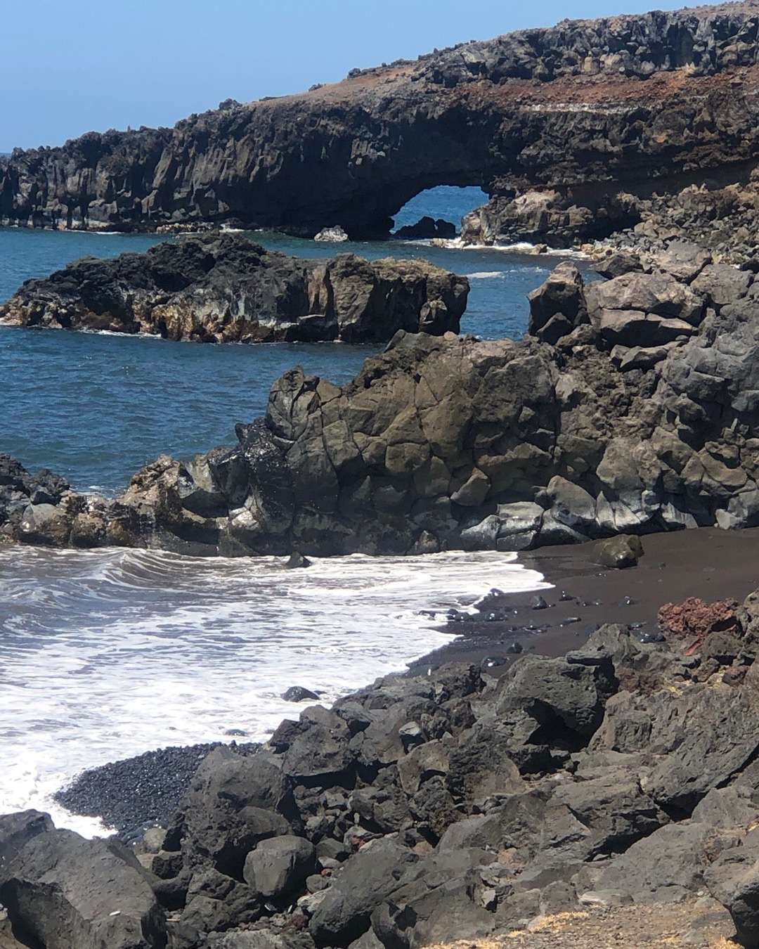 Things you can do in Hawaii for couples Black sand beach with rocks and arch